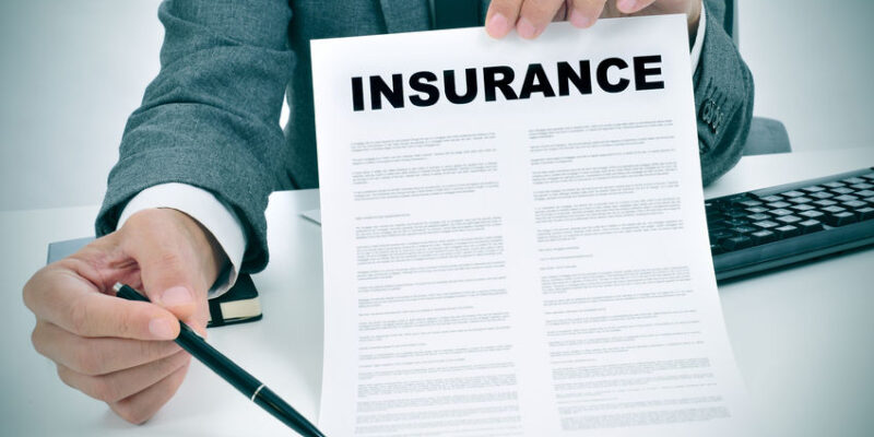 34523365 - a young man in suit in his office showing an insurance policy and pointing with a pen where the policyholder must to sign